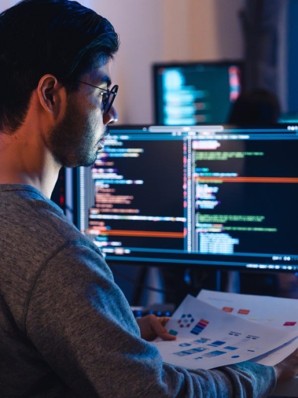 Asian,Software,Developers,Working,On,Multiple,Screens,Displaying,Code,And